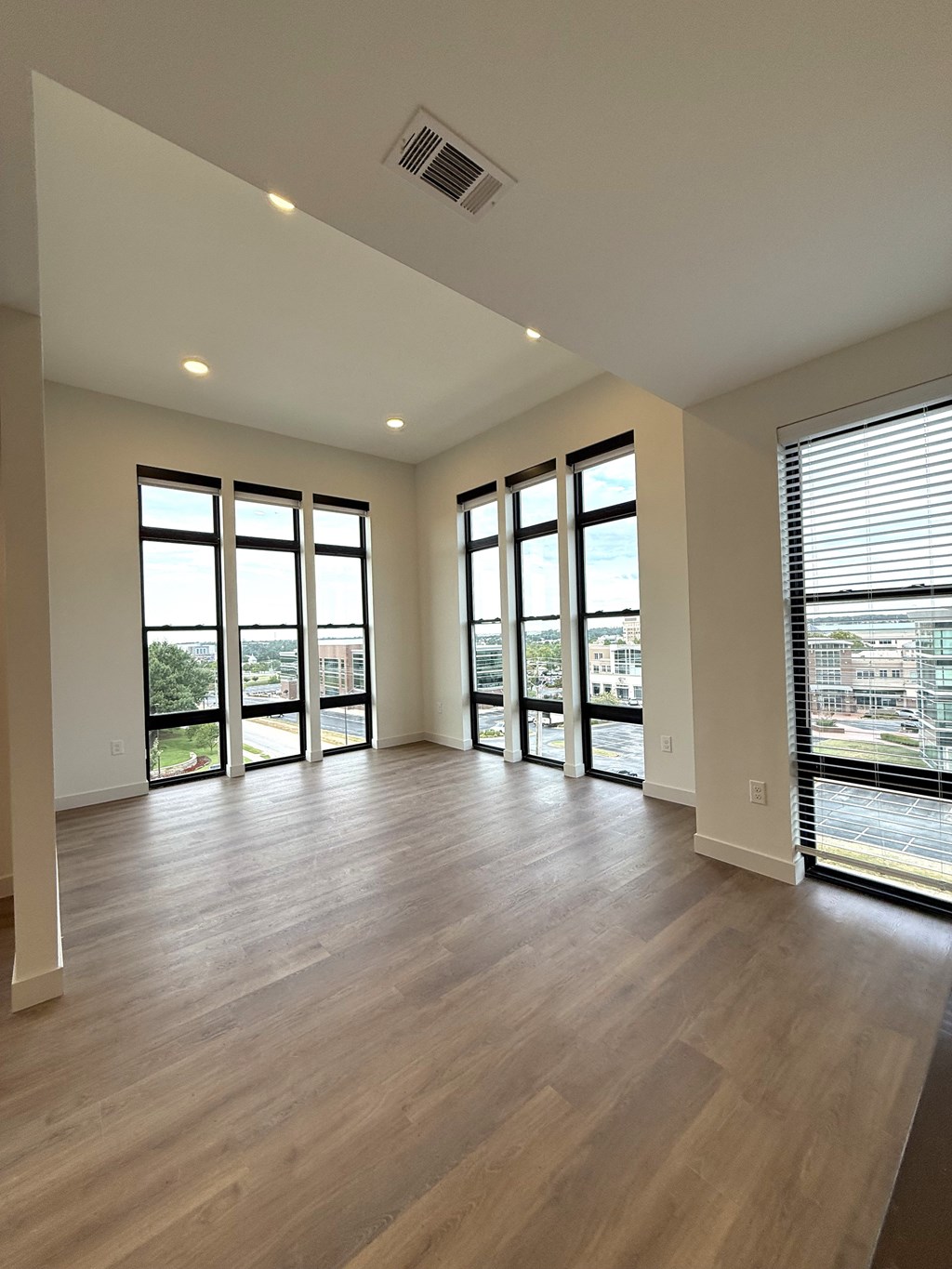 A spacious room with wooden floors and large windows.
