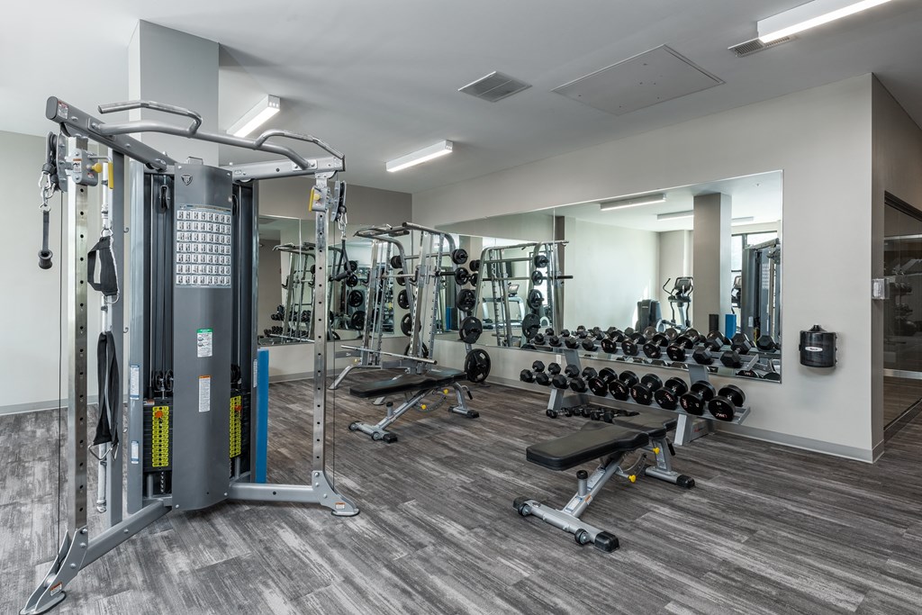 a gym with weights and cardio equipment in a building with white walls at Hibernia Apartments, Missouri