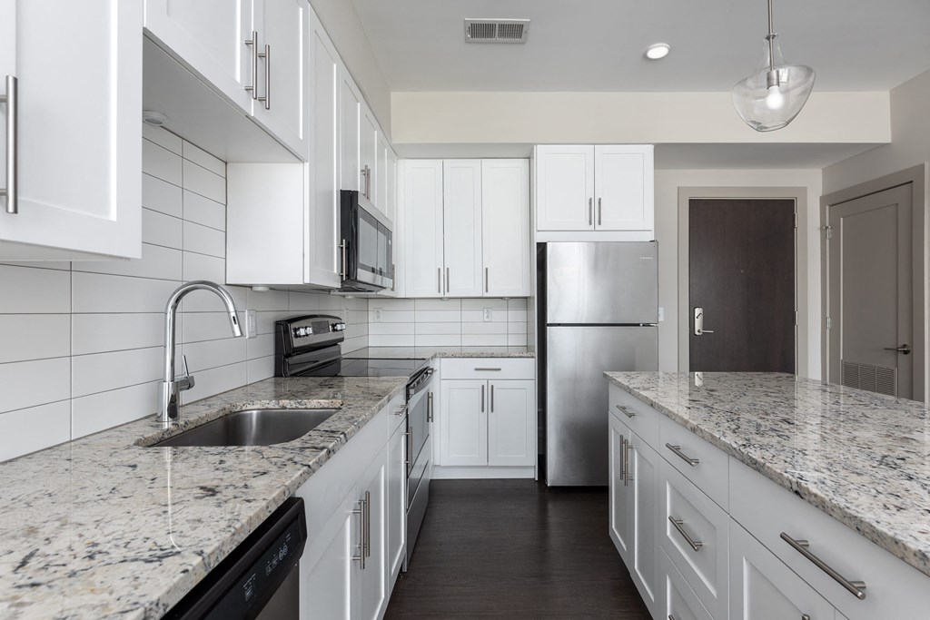 Hibernia kitchen with white cabinets, white tile backsplash, granite countertops and stainless steel appliances at Hibernia Apartments, St Louis, MO