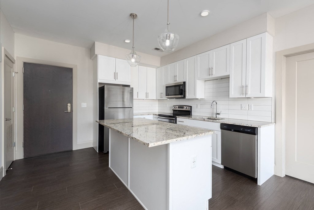 Hibernia kitchen with white cabinets, white tile backsplash, granite countertops and stainless steel appliances at Hibernia Apartments, St Louis, MO, 63139
