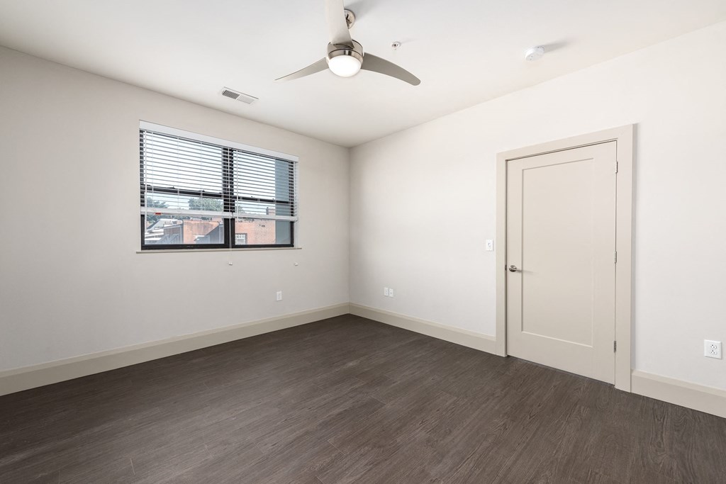 Hibernia bedroom with rich vinyl plank flooring, oversized windows with white blinds and ceiling fan at Hibernia Apartments, Missouri