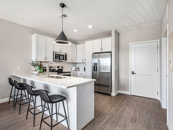 a kitchen with white cabinets and a white island with three black stools - Photo Gallery 33