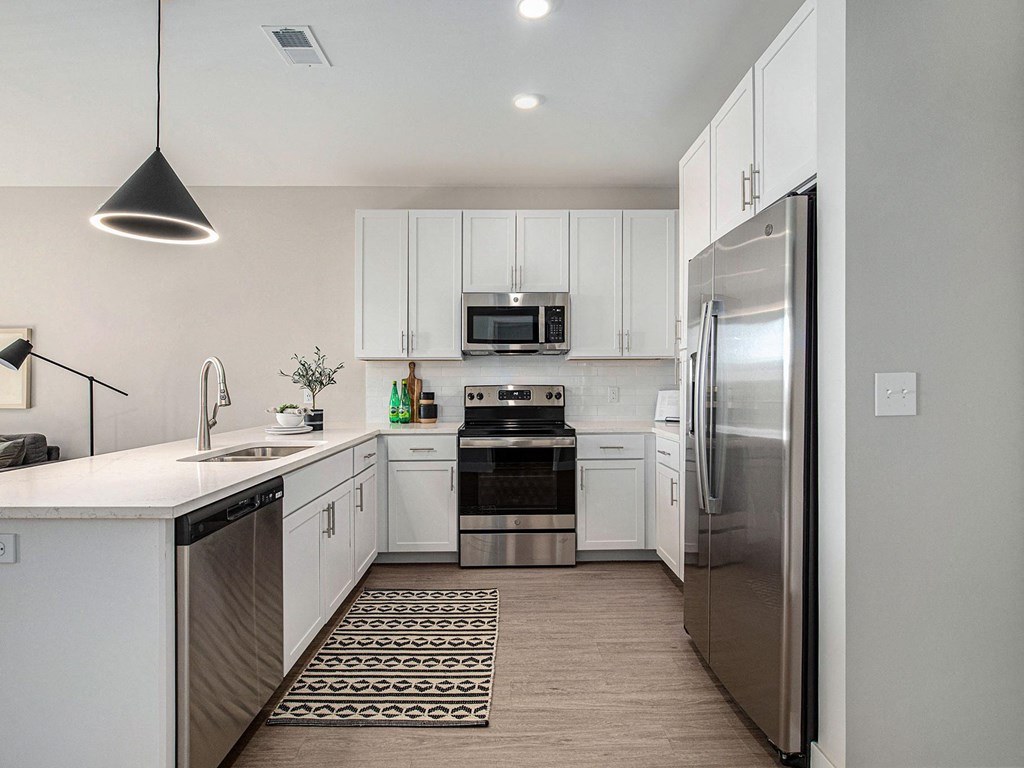 a kitchen with white cabinets and stainless steel appliances  at Signature at West Pryor, Lee's Summit