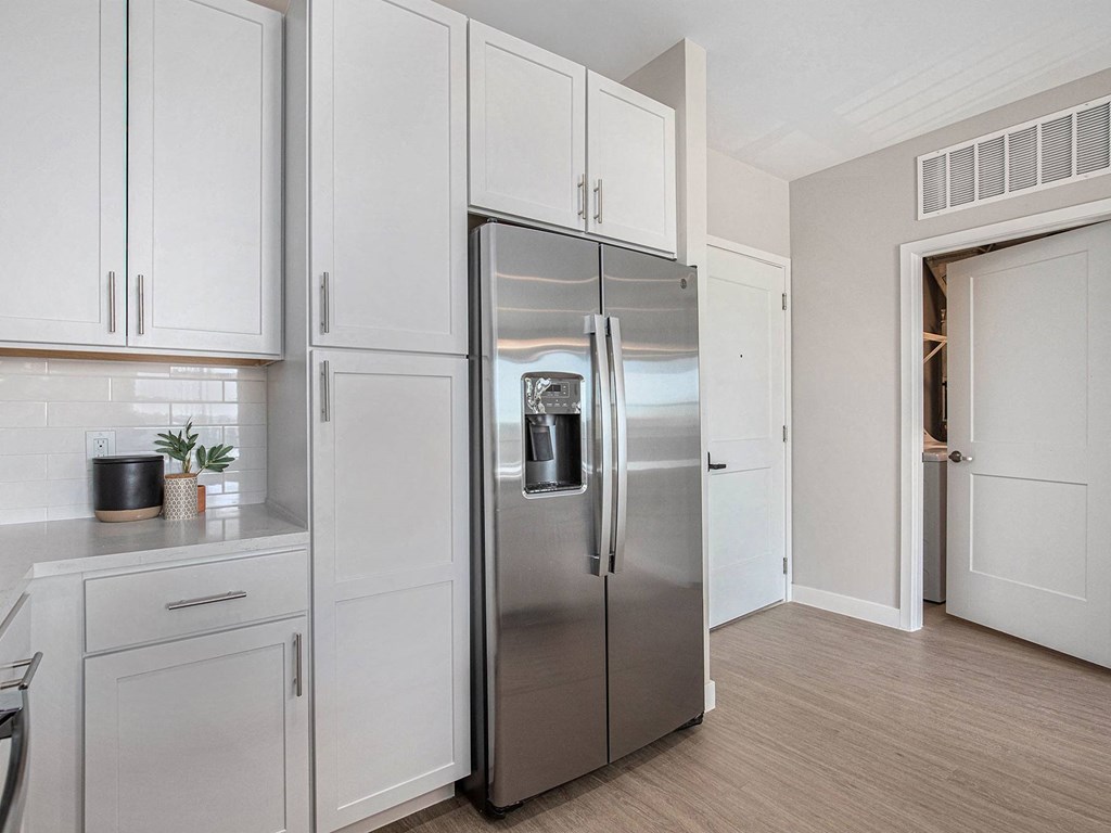 a kitchen with white cabinets and a stainless steel refrigerator  at Signature at West Pryor, Lee's Summit