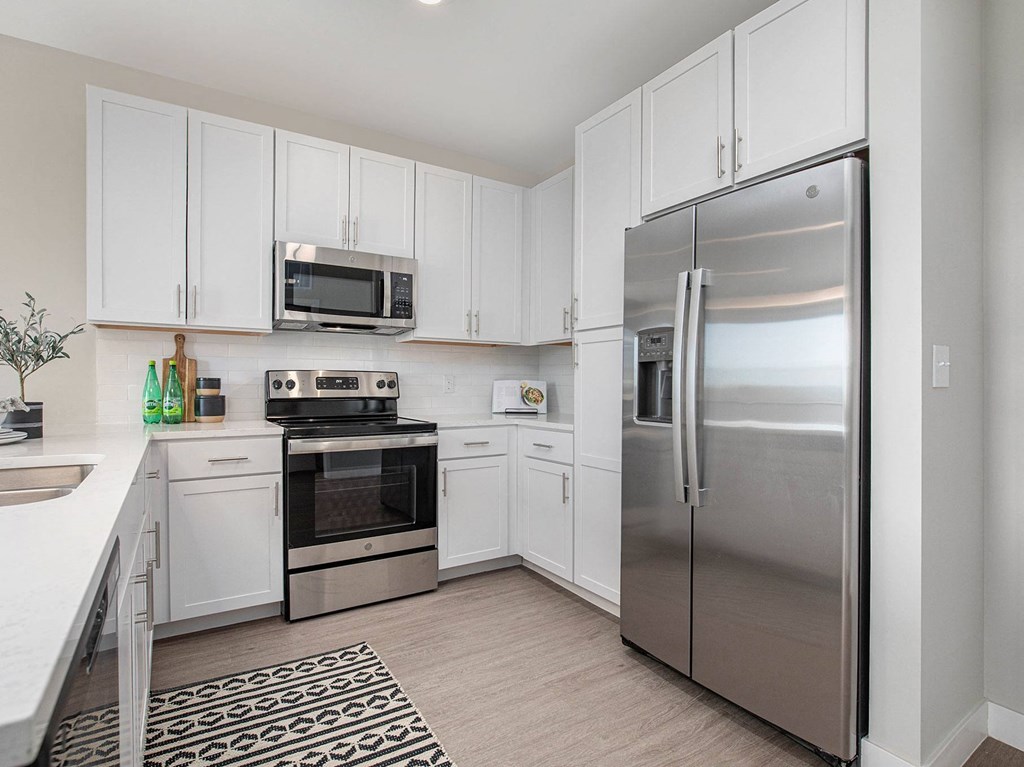 a kitchen with white cabinets and stainless steel appliances  at Signature at West Pryor, Lee's Summit, Missouri