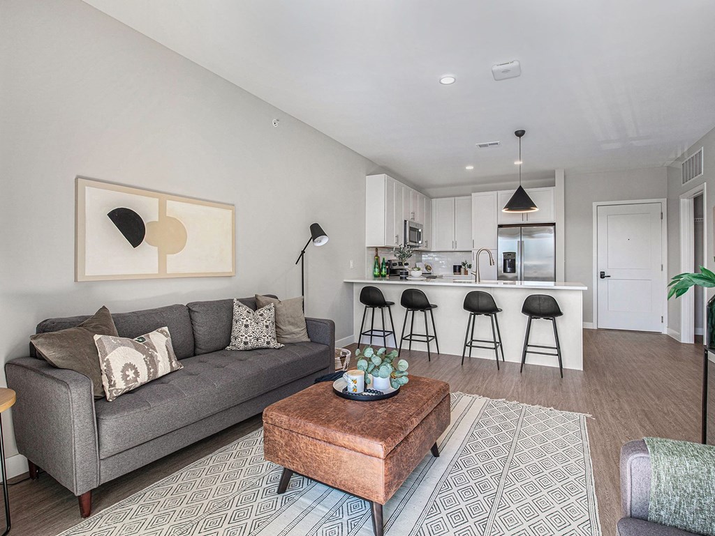 a living room with a gray couch and a coffee table in front of a kitchen with a  at Signature at West Pryor, Lee's Summit, 64081