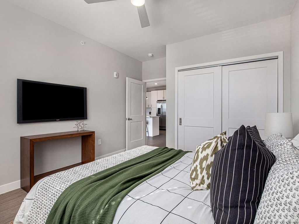 a bedroom with a large bed and a flat screen tv on the wall  at Signature at West Pryor, Lee's Summit, MO