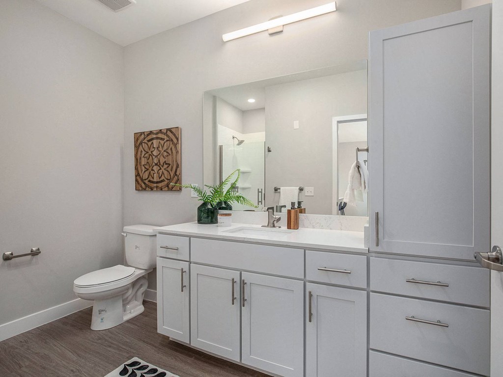 a bathroom with white cabinets and a white toilet  at Signature at West Pryor, Lee's Summit