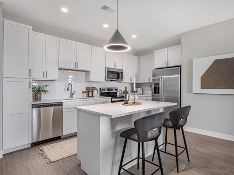 a kitchen with white cabinets and a white island with two stools