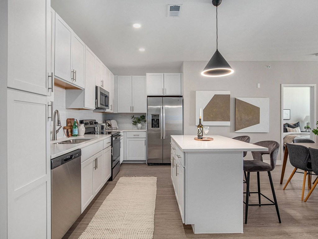 a white kitchen with white cabinets and stainless steel appliances  at Signature at West Pryor, Lee's Summit