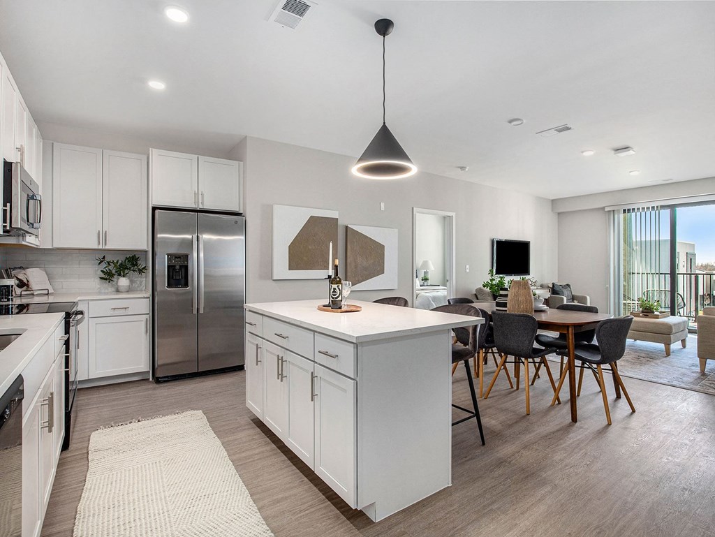 a kitchen and living room with white cabinets and stainless steel appliances  at Signature at West Pryor, Lee's Summit, Missouri
