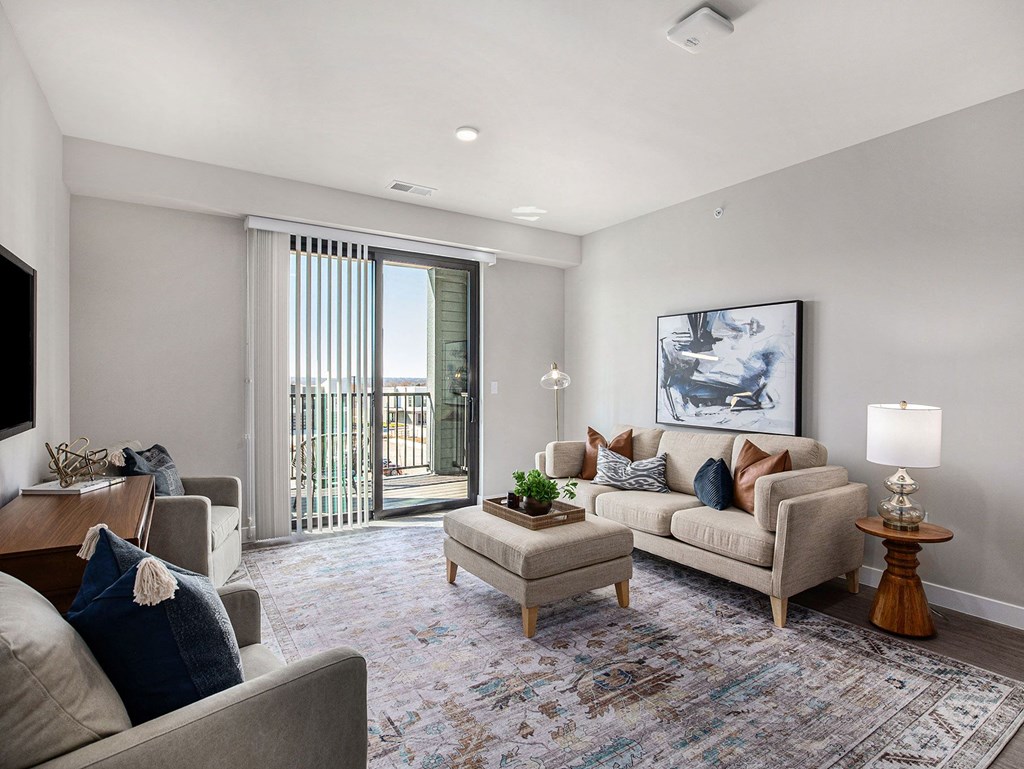 a living room with a sliding glass door leading to a balcony  at Signature at West Pryor, Lee's Summit, MO