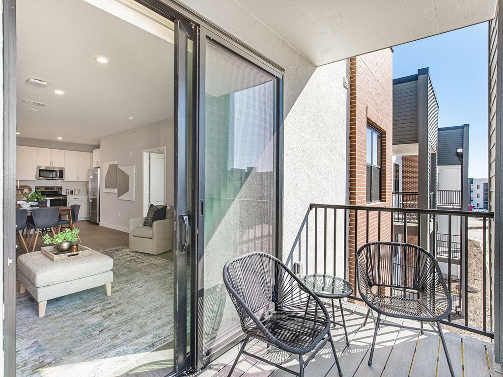 a balcony with two chairs and a table  at Signature at West Pryor, Missouri