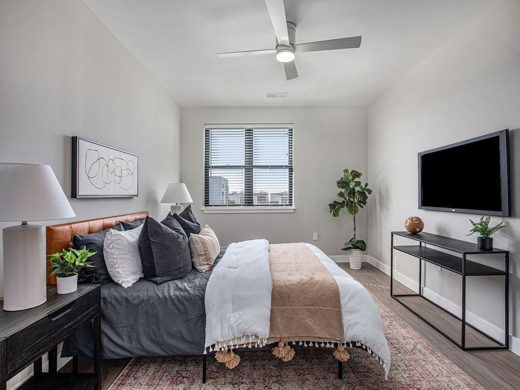 a bedroom with a large bed and a flat screen tv  at Signature at West Pryor, Lee's Summit, Missouri