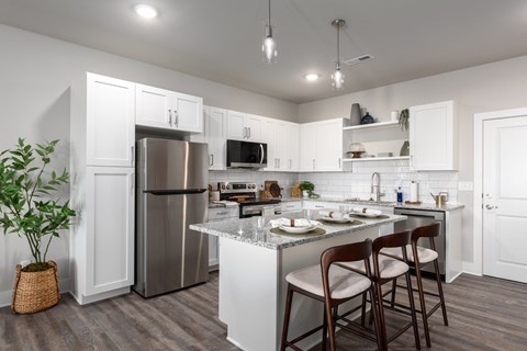 A kitchen with a refrigerator, microwave, and a counter with chairs at Hawk Ridge Apartments, Lake St. Louis, Missouri, 63367