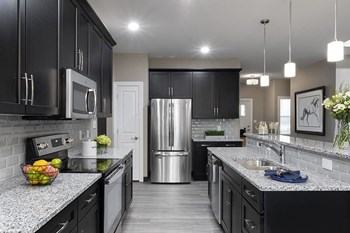 kitchen with dark cabinets, island and stainless steel fridge and microwave - Photo Gallery 3