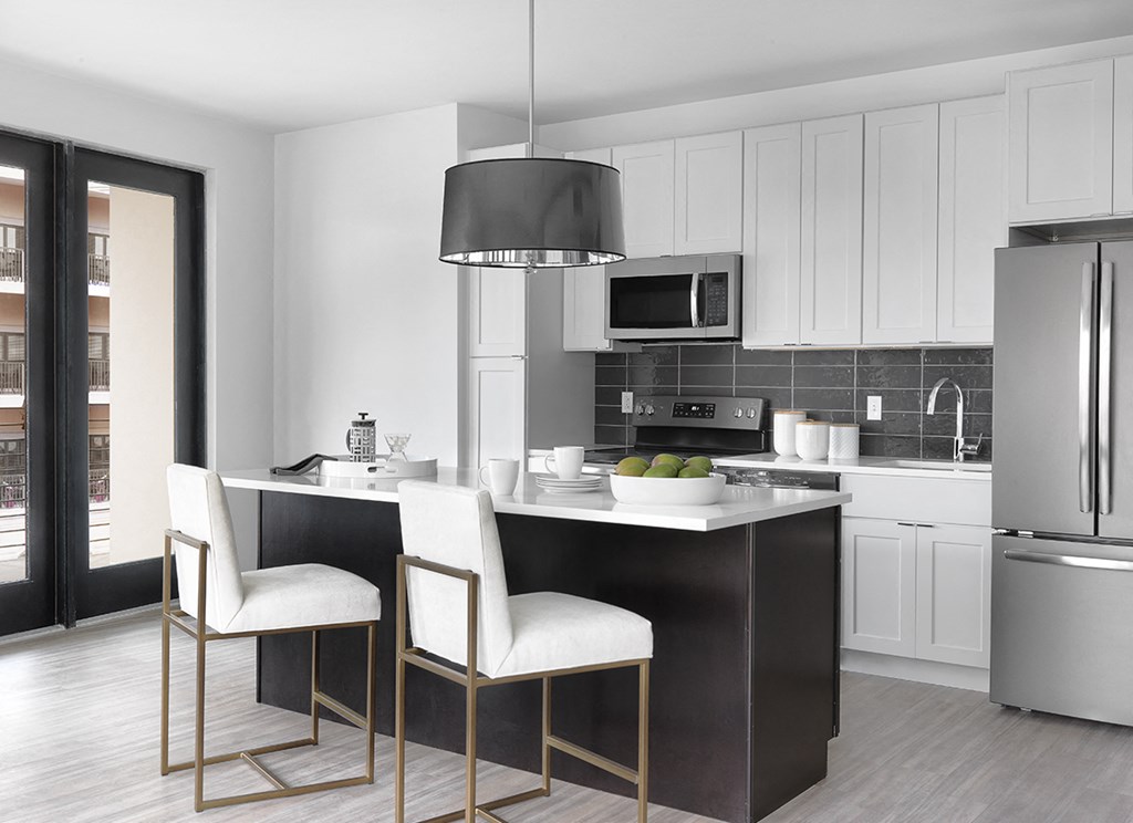 Modern kitchen with white cabinet, stainless steel appliances, island with seating and modern light fixture at The Euclid, St Louis, MO, Missouri