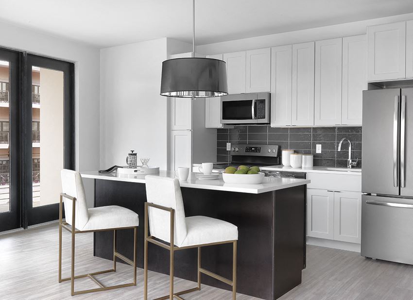 Euclid modern kitchen with white cabinet, stainless steel appliances, island with seating and modern light fixture