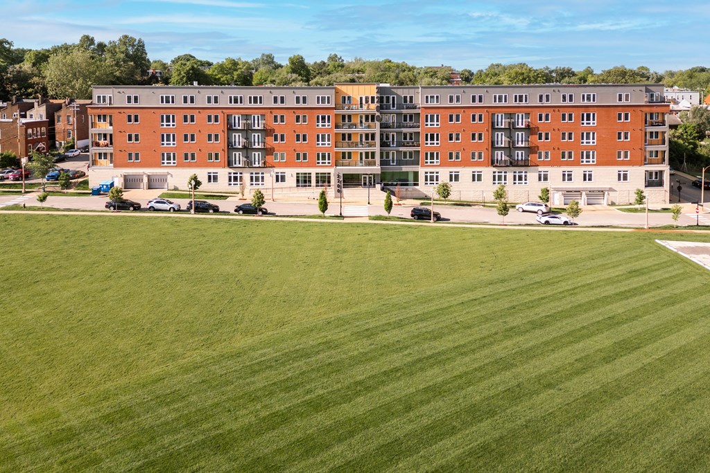 A large grassy field in front of a red brick building.