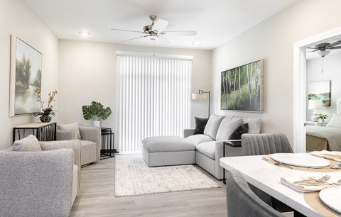 A living room with a grey couch, a white table, and a painting on the wall.