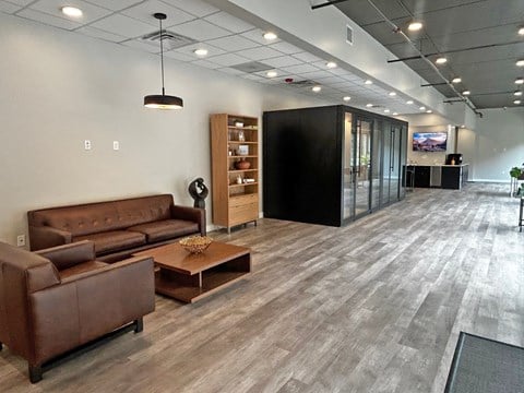 A modern office space with a brown leather sofa and a wooden coffee table.