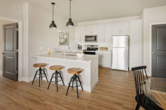 a kitchen with white cabinets and a bar with three stools