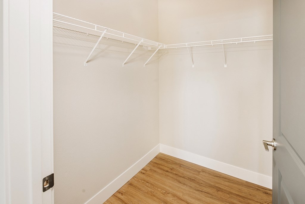 a bedroom with white walls and a wood floor and a closet with white hangers at 44 West Luxury Living, Valley Park, MO, 63088