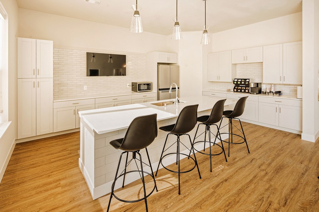 a large white kitchen with a white island and black chairs at 44 West Luxury Living, Valley Park