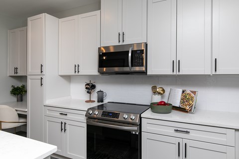 A kitchen with white cabinets and a black oven.