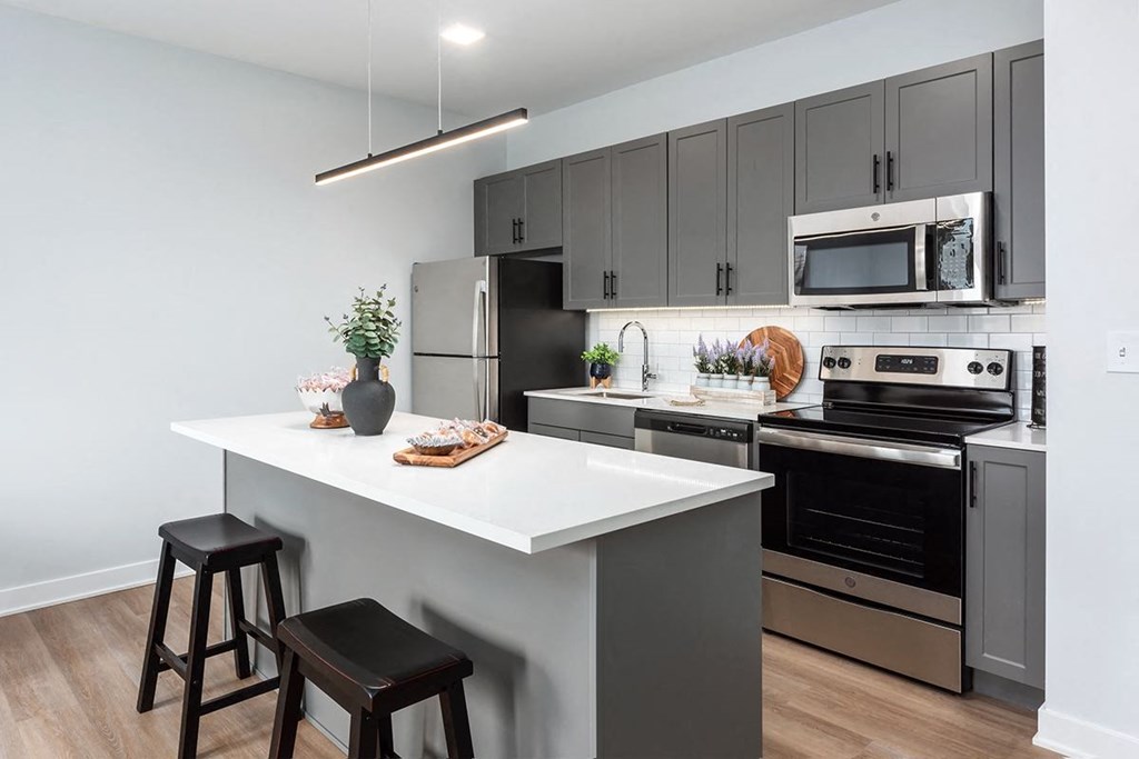 model kitchen with stainless steel appliances, plank flooring, kitchen island and at Steelcote Square, St. Louis, MO, 63103