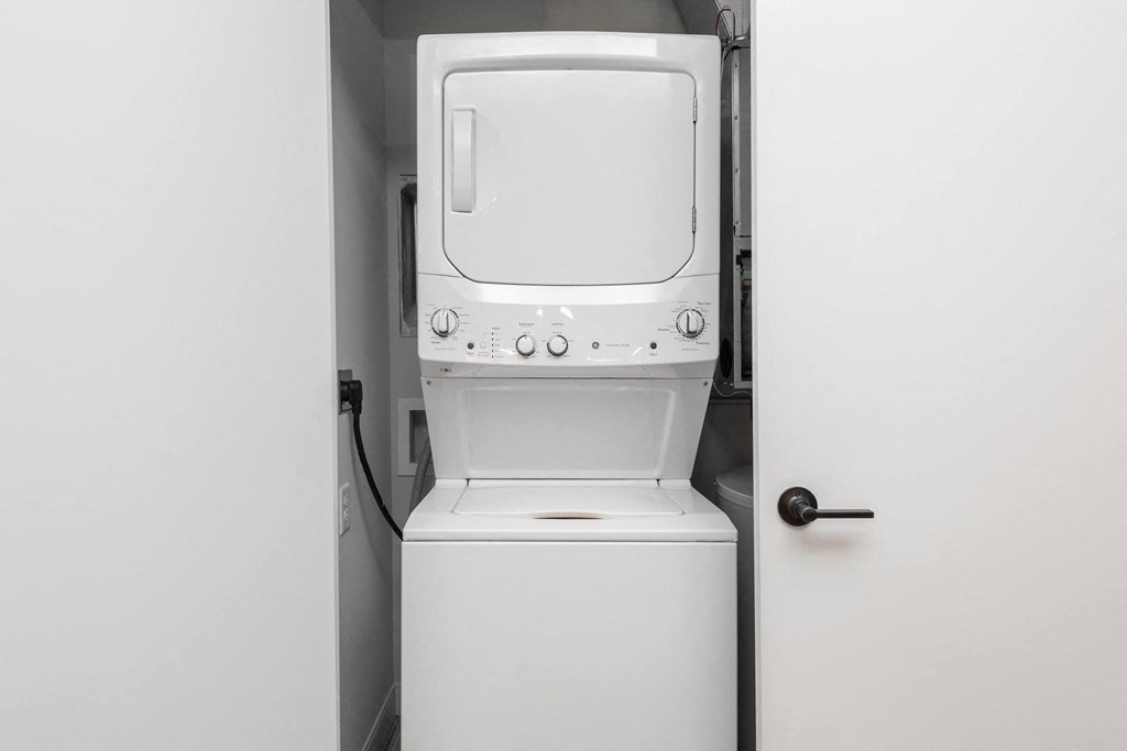 a white washer and dryer in a room with a door at The Flats & Terraces at Wildhorse Village, Missouri