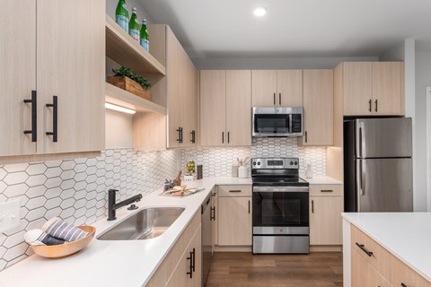 a modern kitchen with white counter tops and wooden cabinets at The Flats & Terraces at Wildhorse Village, Chesterfield, 63005