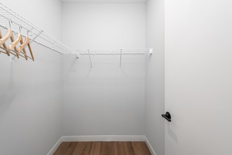 an empty closet with white walls and wood flooring at The Flats & Terraces at Wildhorse Village, Chesterfield