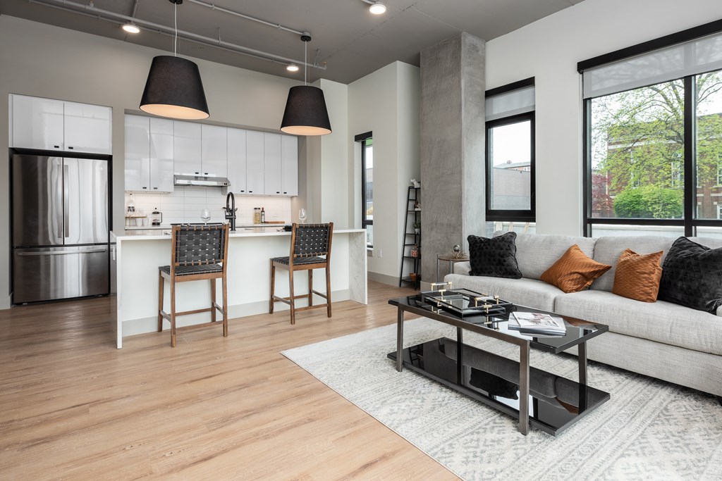 a living room with a couch and a coffee table in front of a kitchen at Bemiston Place Apartments, Clayton, MO 63105