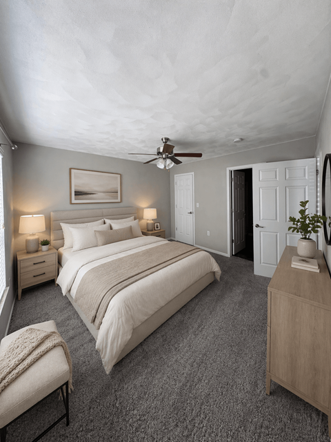 A bedroom with a large bed, a bench, and a ceiling fan.