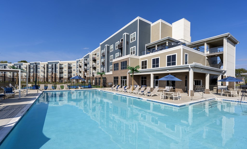 A large swimming pool in front of a multi-story residential building.