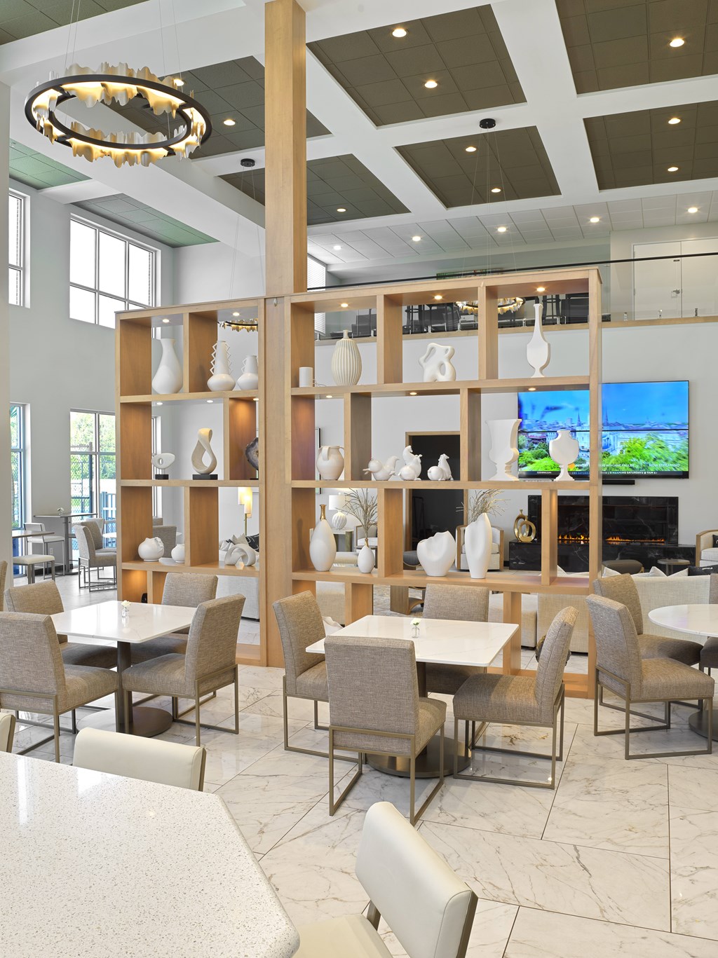 A room with a white table and chairs with a shelf in the background.