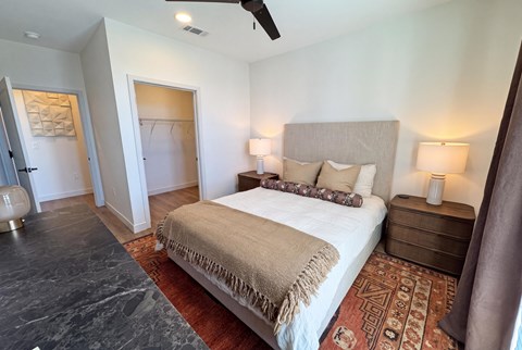 A bedroom with a large bed and a rug on the floor.