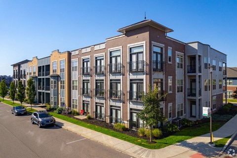 A row of modern apartment buildings with cars parked in front.