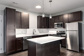 A modern kitchen with dark brown cabinets and stainless steel appliances.