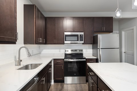 A modern kitchen with dark brown cabinets and stainless steel appliances.