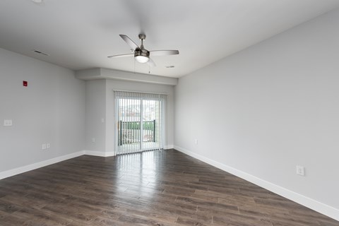 A room with a ceiling fan and sliding glass doors.