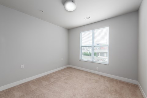 A room with a window and a carpeted floor.