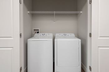 Two white front load washing machines in a laundry room.