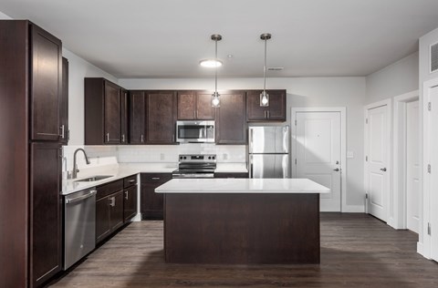 A modern kitchen with dark brown cabinets and a white countertop.