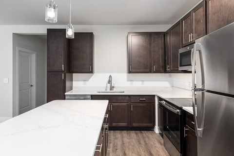 A kitchen with dark brown cabinets and a stainless steel refrigerator.