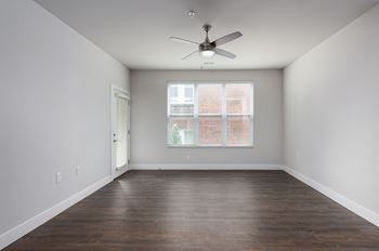 A room with a ceiling fan and a window with blinds.