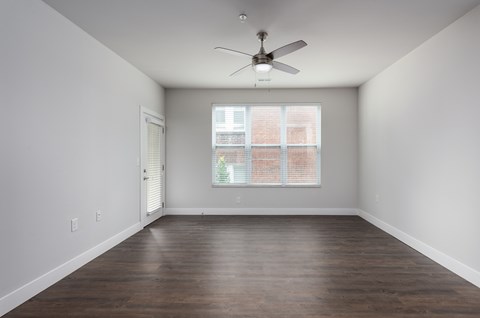 A room with a ceiling fan and a window with blinds.