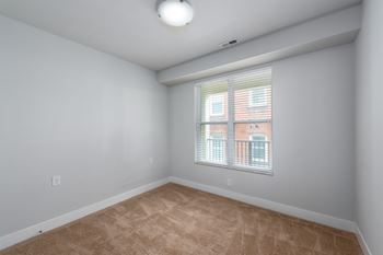 A room with a carpeted floor and a window with blinds.