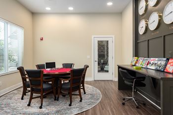 A conference room with a table and chairs and a wall of clocks.